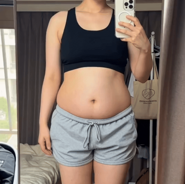鏡の前でお腹まわりを確認する女性の様子