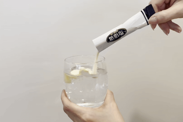さらば糖脂塩の粉末をコップの水に入れる様子